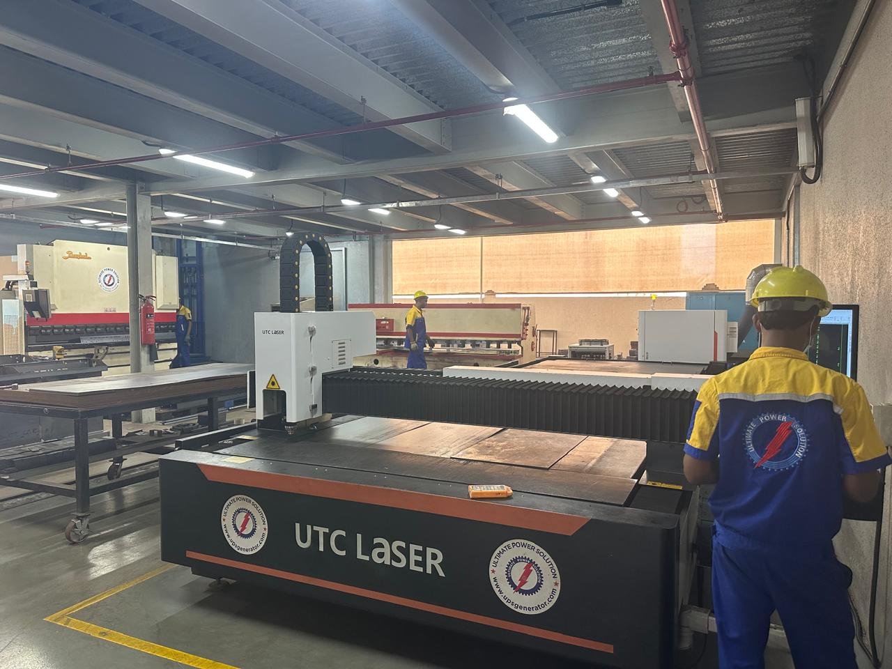 Operator at the control station of a fiber laser cutting machine on the production floor